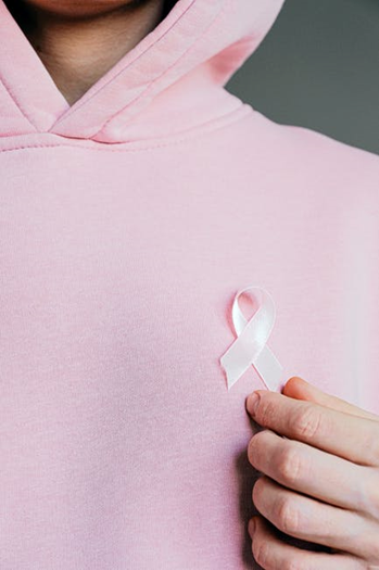 A person in a pinky hoodie wears a pink ribbon to express support for breast cancer survivors.