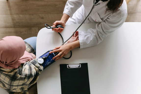 A doctor performs a general physical exam and checks a patient's blood pressure during it.