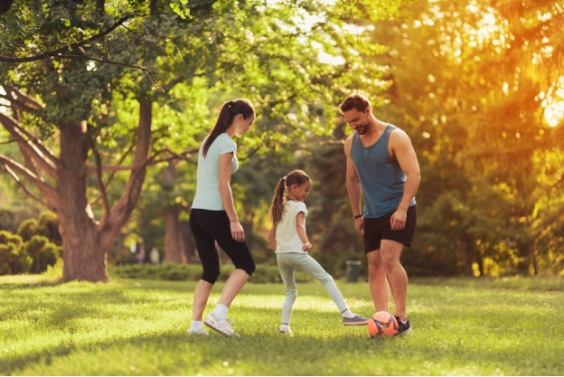 Woman and man with daughter in the park playing soccer