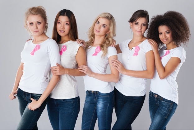 five multi-racial women in blue jeans and white t-shirts with breast cancer survivor ribbons on
