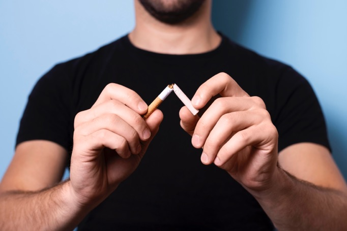 a man breaks a cigarette in half