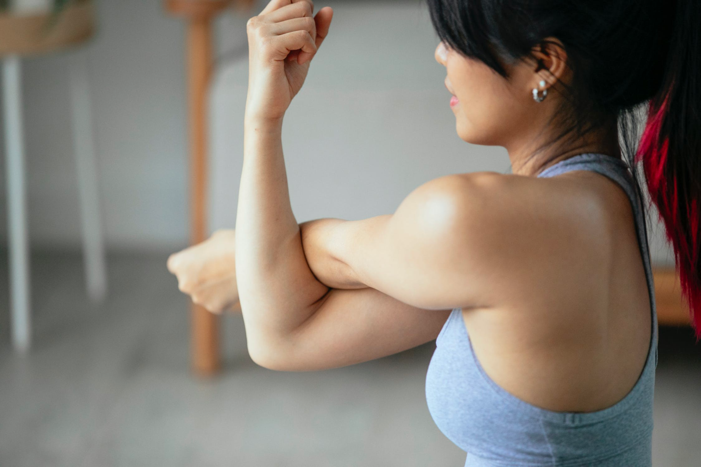 A woman crosses her arm while stretching it across her body.
