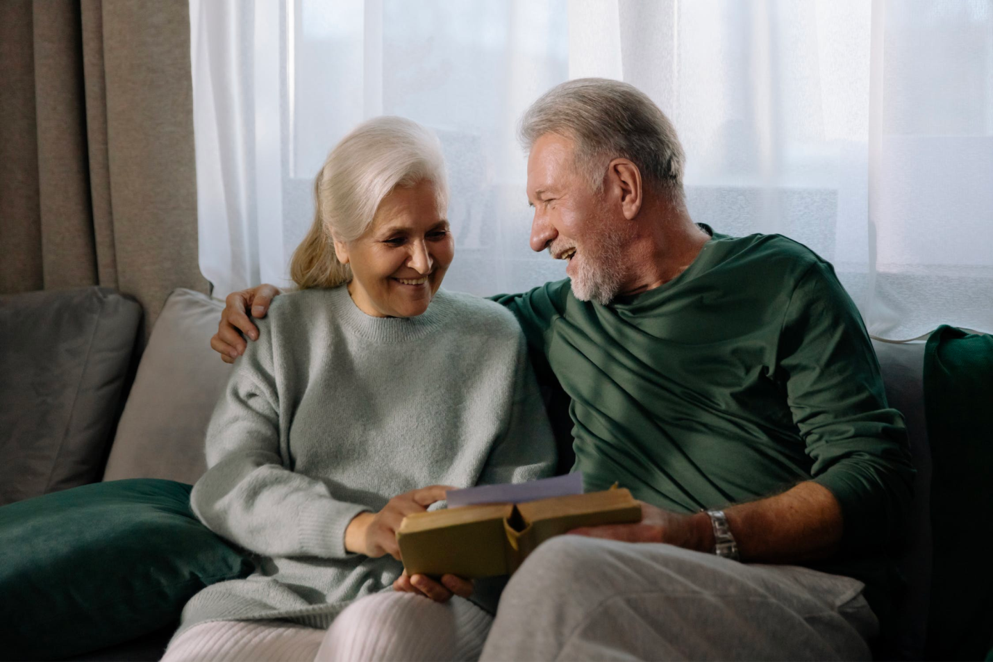 An older couple looks happy and in love while smiling at each other. 
