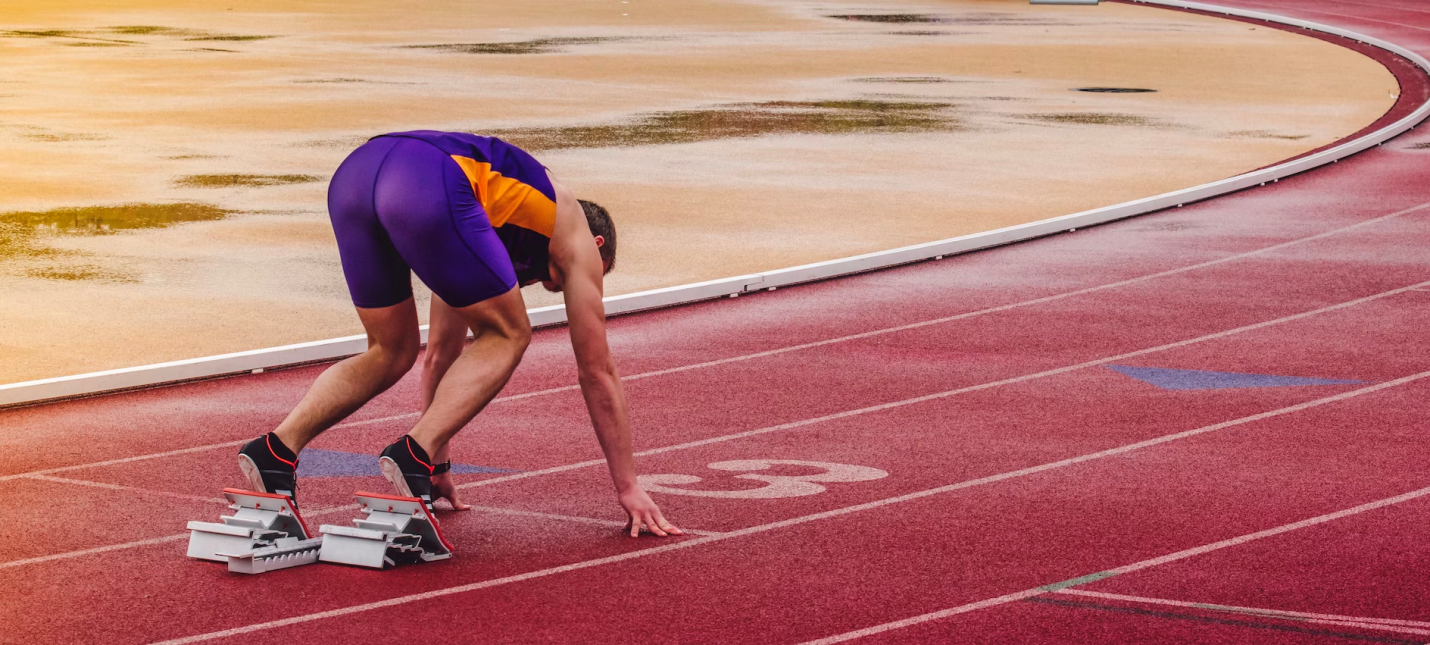 An athlete holds their stance while preparing to run track. 