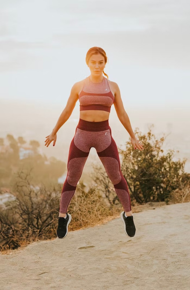 A woman jumps up high while working out. 