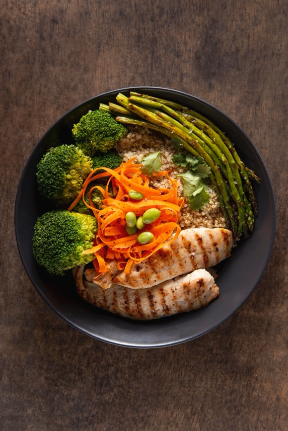 A healthy plate of broccoli, carrots, asparagus, quinoa, and grilled chicken