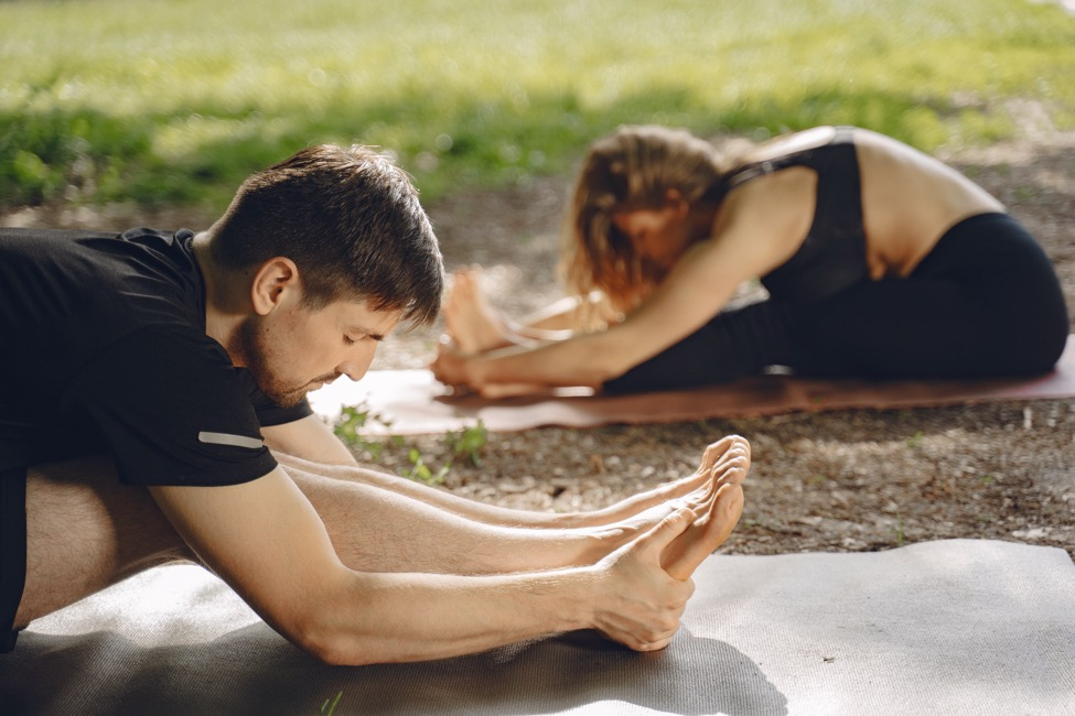 A man and woman stretching on yoga mats.
