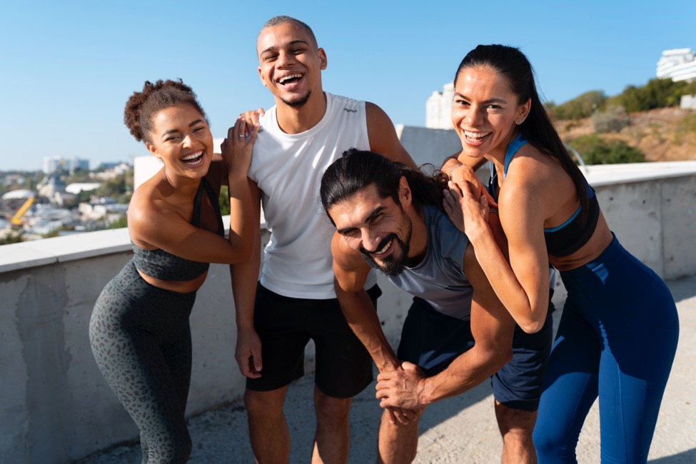 Two men and two women working out on a jogging trail smile at the camera