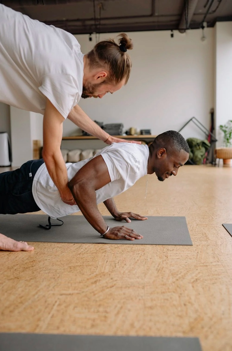 A man performs a plank with assistance. 