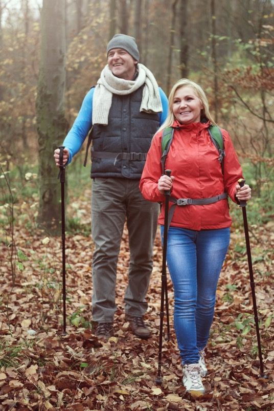 An active older couple hike in the woods together.