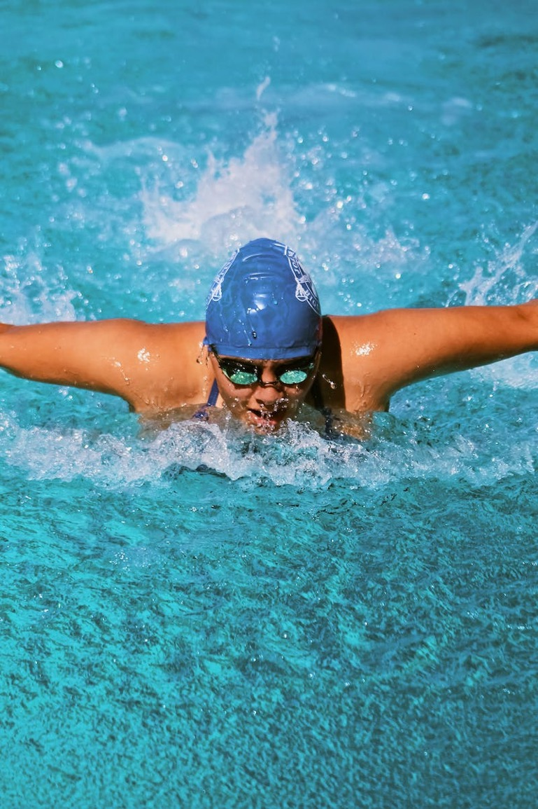 A healthy woman does a butterfly stroke in a pool.